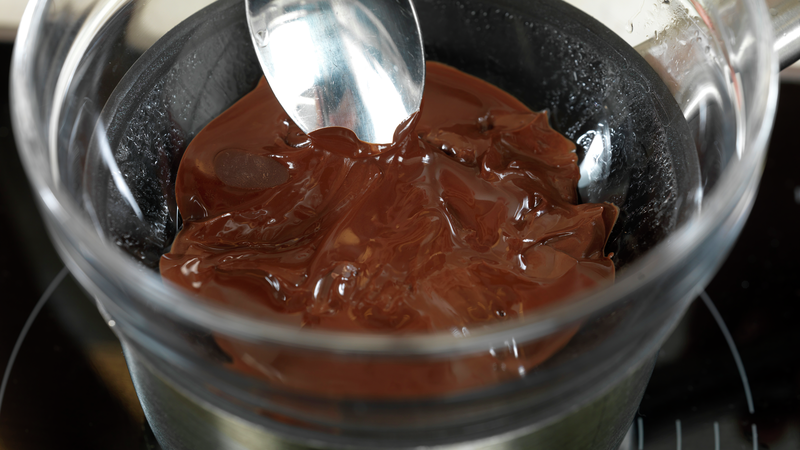 Du kan pirke litt borti sjokoladen med en spiseskje for å se om den er smeltet. Nå kan du også legge i litt kokosfett, og røre det inn. Det gjør sjokoladen mer flytende, og enklere å dekorere konfekten med.