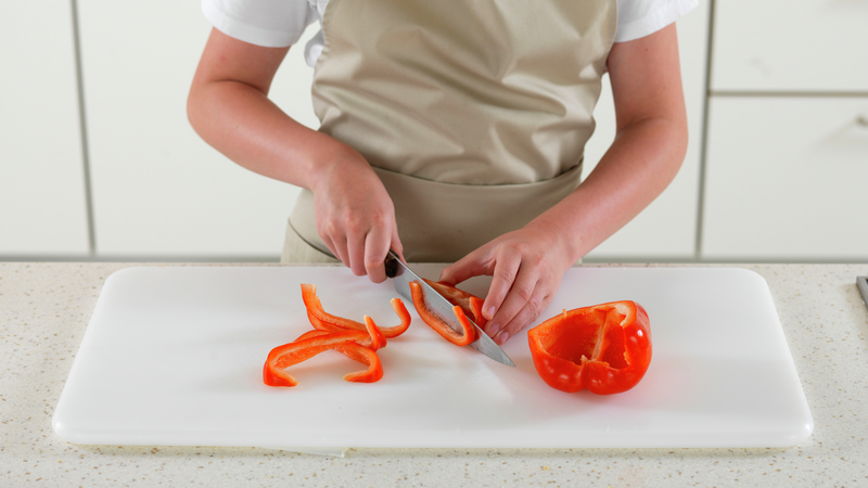 Skjær paprika i strimler på langs. Den paprikaen du ikke bruker, kan du pakke inn i plast og legge i kjøleskapet. Server grønnsaksstavene på et fat eller en tallerken, sammen med hummusen.