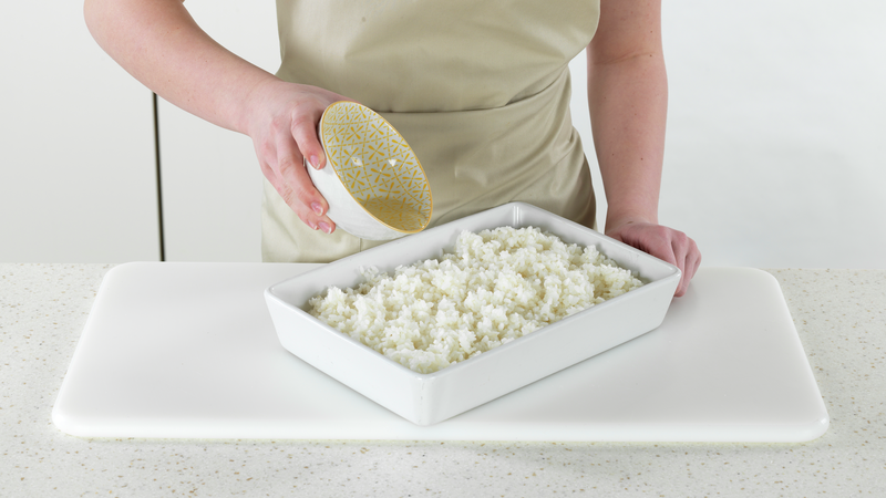 Skru av platen når risen er klar. Ha risen over på et fat med høye kanter. Hell sushieddikken over risen og bland forsiktig inn med en skje eller en sleiv.