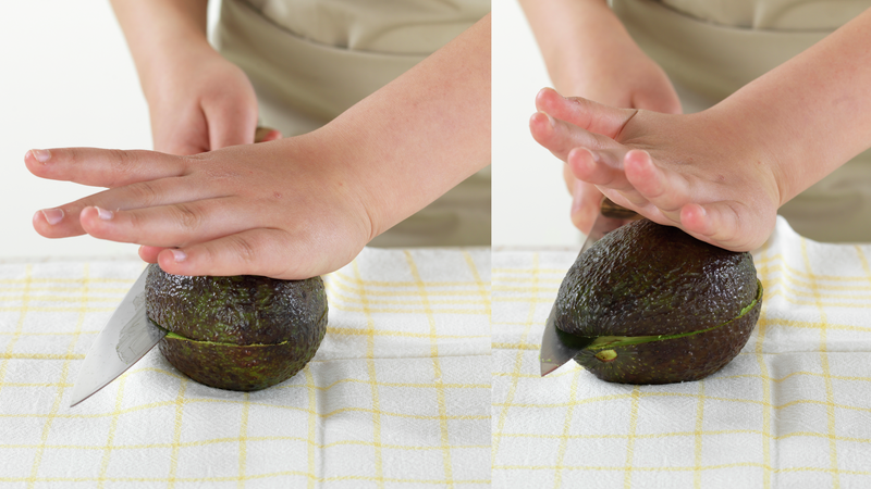 Del avokadoen i to slik: hold den ene hånden på avokadoen mens du bruker kniven og skjærer et snitt langs den ene siden av avokadoen. Vri den så rundt og skjær et snitt langs den andre siden.