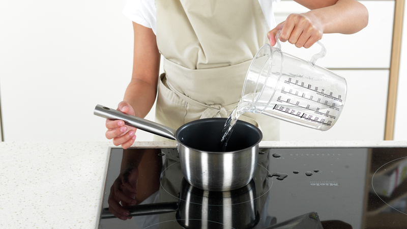 Nå kan du forberede nudelsalaten. Sett en kjele på platen. Bruk et desilitermål, eller en mugge, og fyll kjelen halvfull med vann. Skru platen på fullt.