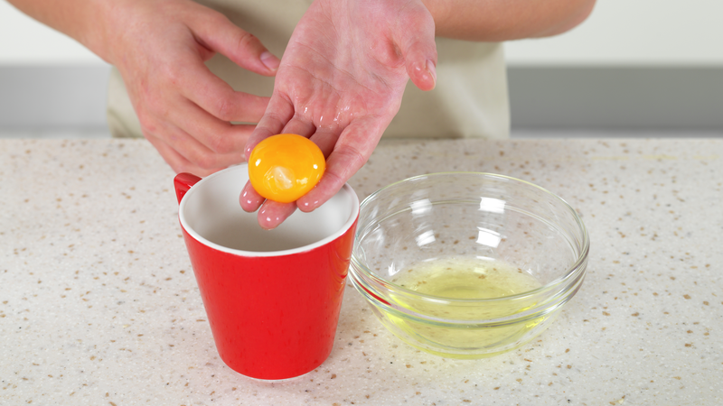 Vask hendene godt, og bruk hånden din til å løfte eggeplommen forsiktig ut av bollen. Legg eggeplommen i koppen.