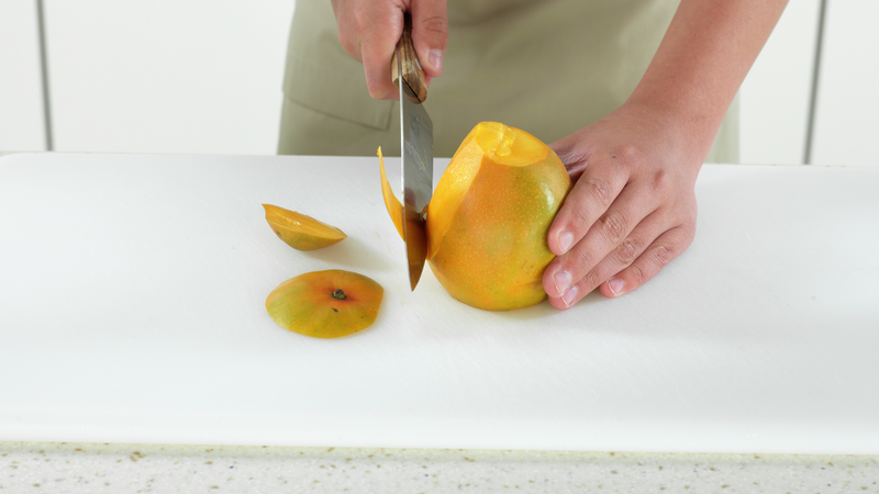 Plasser mangoen stødig på skjærefjølen, med bunnen ned. Skjær av skallet, ved å la kniven gli langs sidene. Prøv å skjær så nærme skallet du klarer, slik at minst mulig havner i søpla.