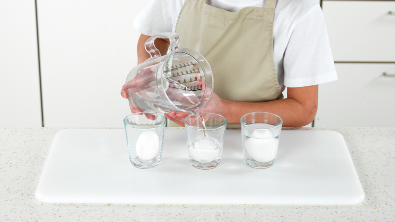 Legg eggene i hvert sitt glass og fyll vann i glassene, slik at du dekker eggene. Bruk et målebeger, eller noe annet du har på kjøkkenet til å helle vann fra.