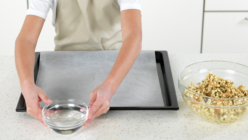 Finn frem et stekebrett og legg på et ark bakepapir. Sett frem en skål med vann.