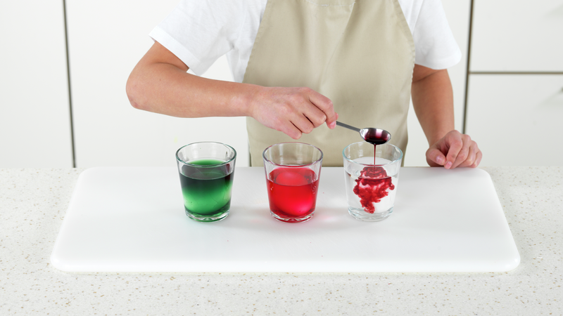 Ha blåbærsaft i ett glass. Rør litt med teskjeen, slik at fargen blander seg med vannet.