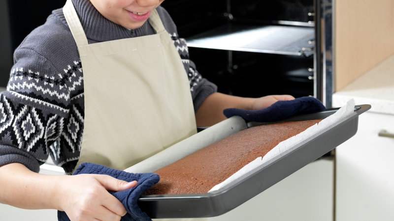 Bruk gryteklutene og ta forsiktig ut langpannen av ovnen. Sett den på gryteunderlaget og la kaken avkjøle seg.