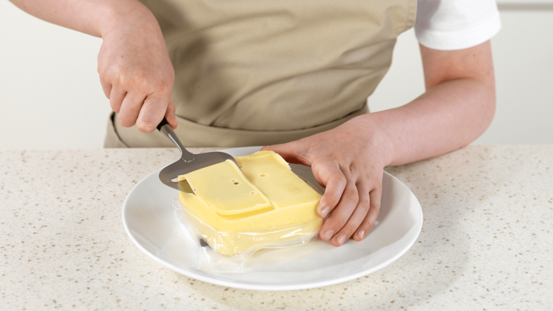 Skjær hvitost med en ostehøvel.