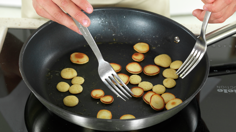 Når pannekakerøren begynner å stivne (piple på overflaten), så kan du sjekke om pannekaken har fått en fin gyllen brunfarge på undersiden. Bruk to gafler til å snu pannekakene.