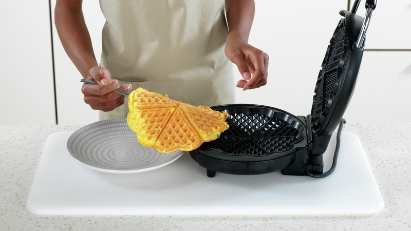 Bruk en gaffel og ta omelettvaffelen ut av jernet, når den er ferdig stekt. Legg den over på en tallerken.